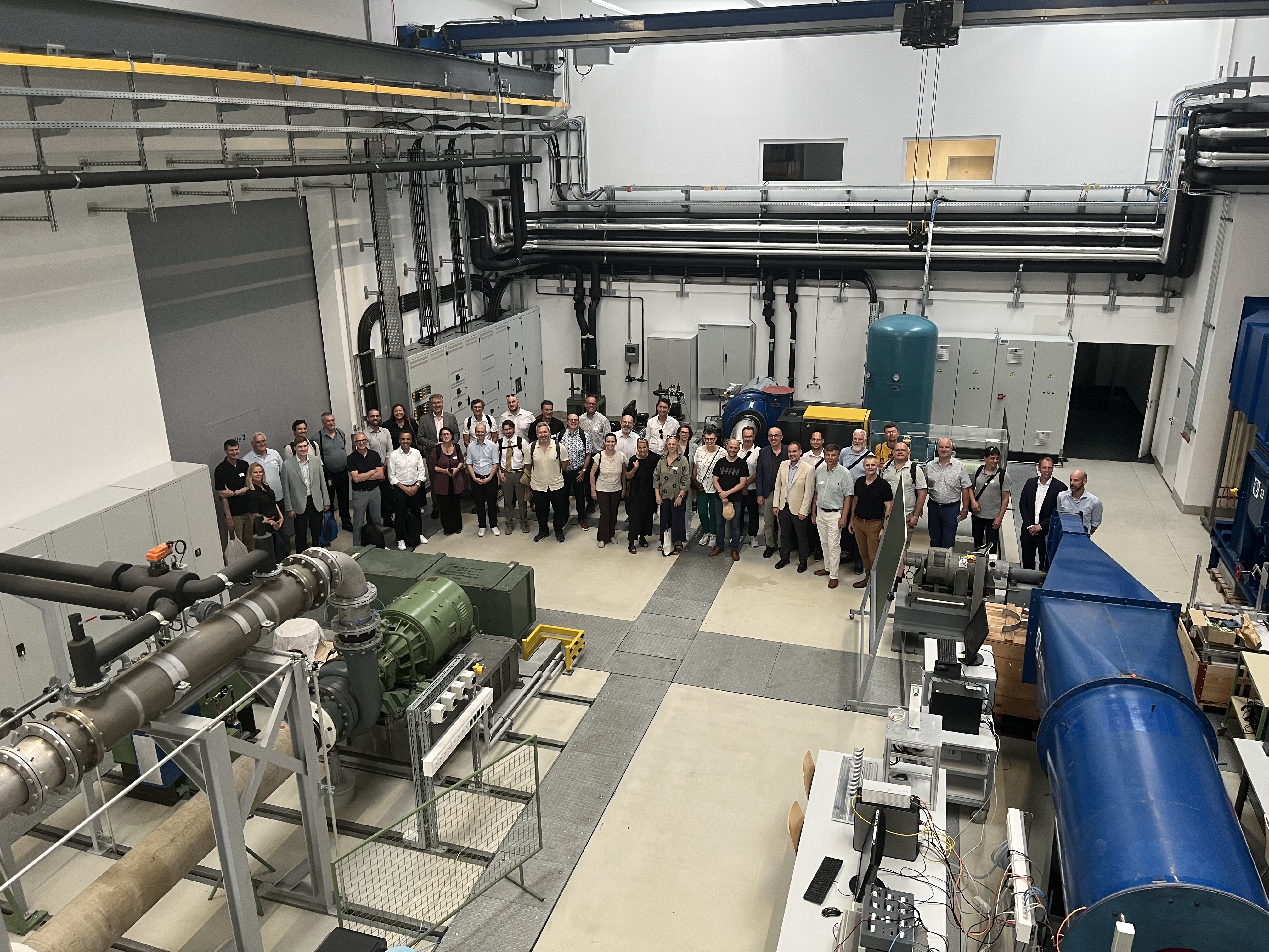 Gruppenfoto mit mehreren Personen in großer Maschinenhalle